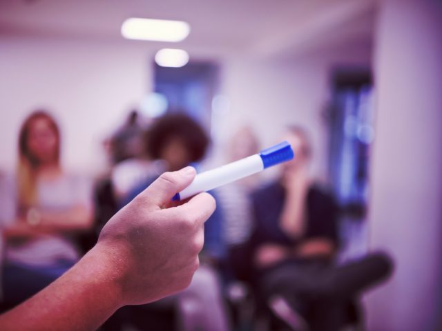 close up of teacher hand with marker while teaching lessons in school classroom to multiethnic students